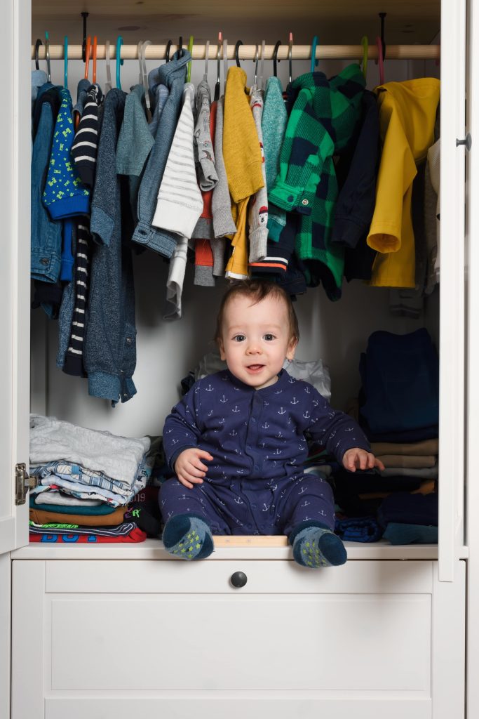 Niño sentado dentro de un armario para adultos.